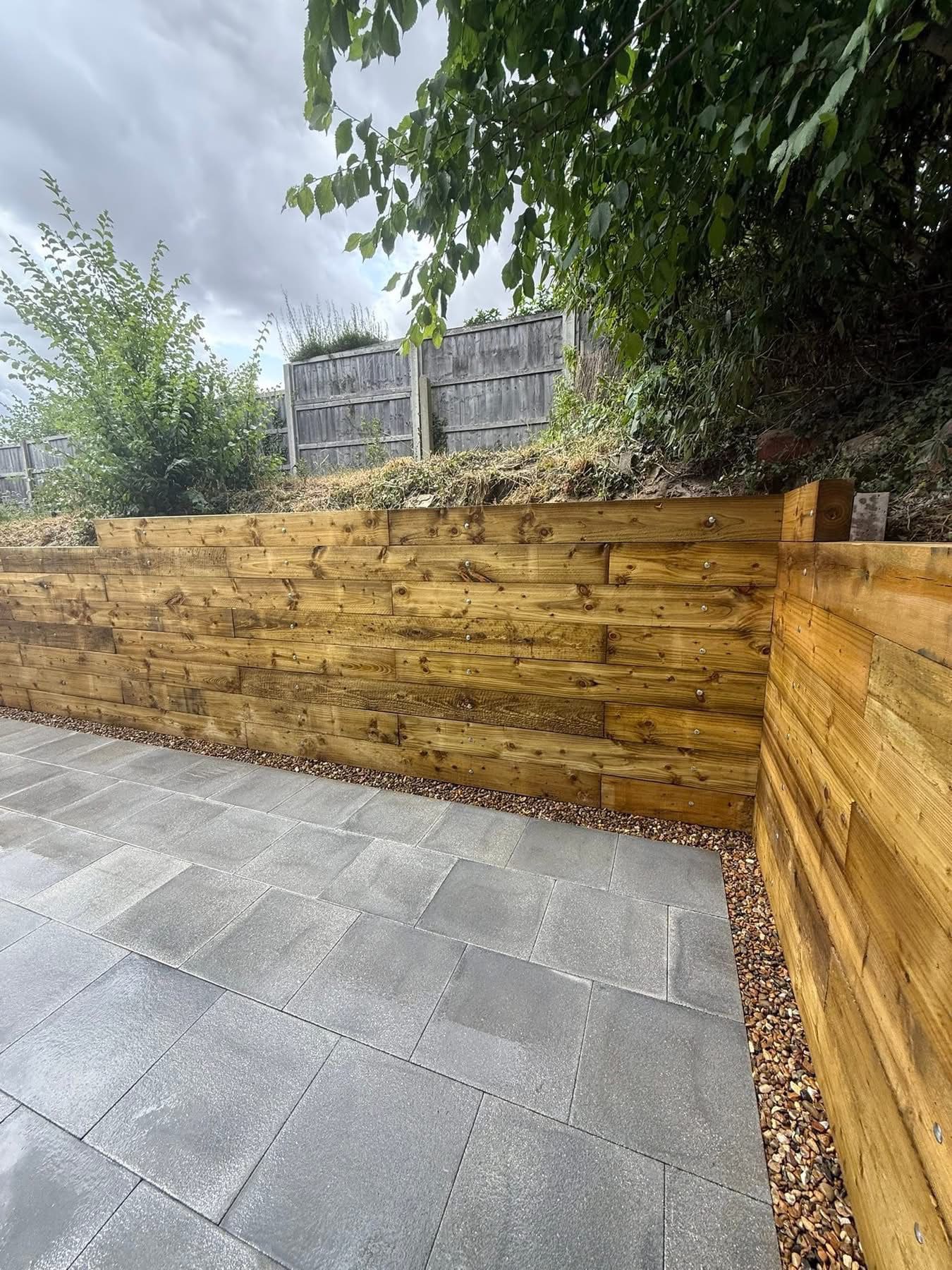 Timber sleeper retaining wall with porcelain patio below